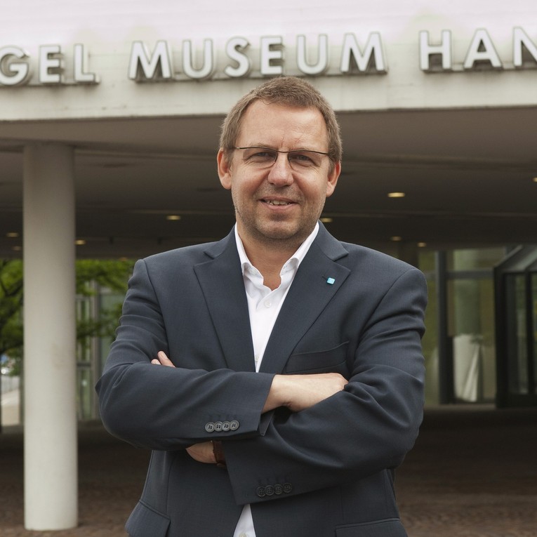 Reinhard Spieler mit verschränkten Armen vorm Eingang des Sprengel Museums Hannover