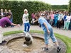 Drei Jungen vollführen Wasserspiele im Großen Garten in Herrenhausen. Zahlreiche Kinder und Erwachsene im Hintergrund beobachten sie dabei.