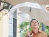 Der Künstler Paul DeMarinis steht mit einem durchsichtigen Regenschirm in der Hand unter seiner Installation und schaut nach oben