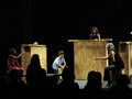 Blick auf eine Bühne; vier Kinder trommeln auf Holzkästen